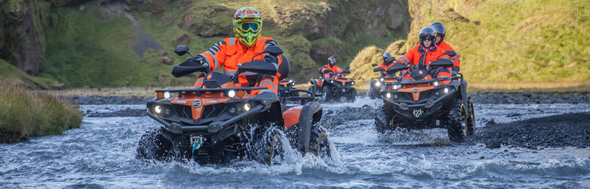 Personer på firehjulinger som krysser en bekk på Island.