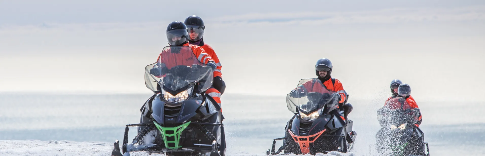 En gruppe som kjører snøscooter på en isbre på Island.