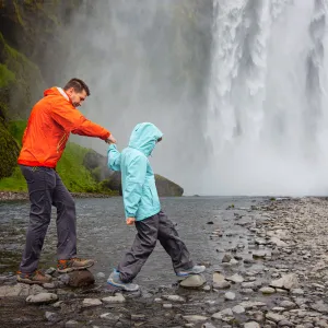  Far og sønn besøker fossen Skogafoss på Island